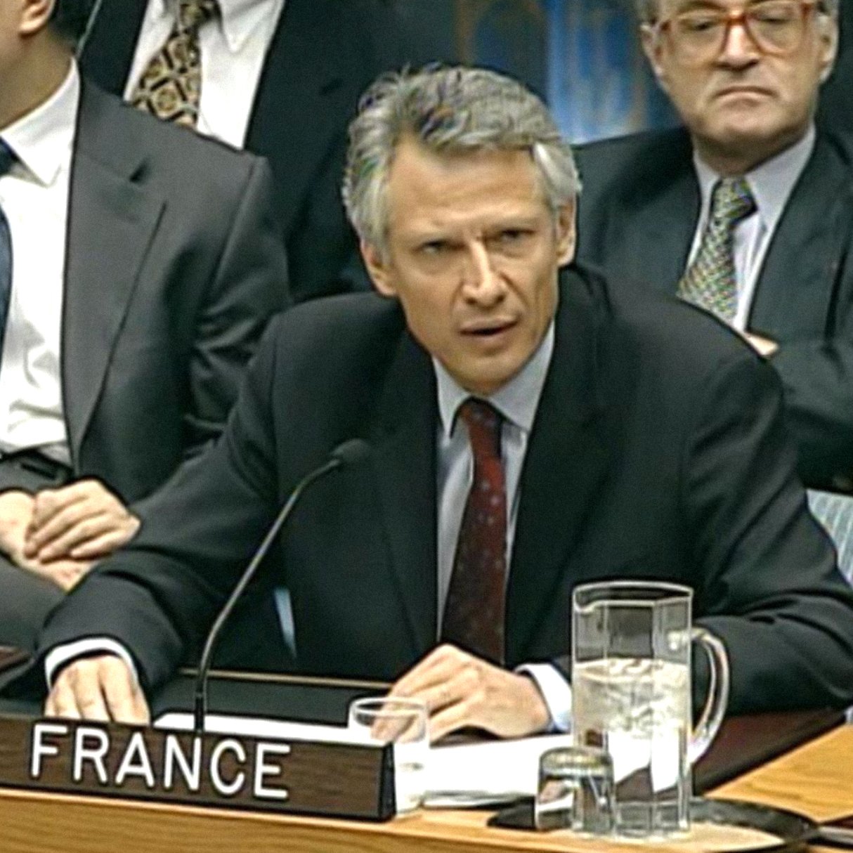 Homme en costume, sérieux, représentant la France lors d'une réunion officielle.