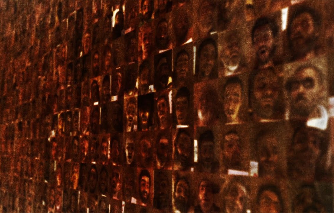 L'image montre une multitude de visages assemblés en un collage dense. Les visages semblent provenir de diverses personnes, chacun ayant une expression différente, ce qui crée une texture visuelle riche. L'éclairage est légèrement tamisé, ce qui donne à l'ensemble un aspect à la fois mystérieux et profond, plongeant le spectateur dans une réflexion sur l'identité et la diversité humaine.