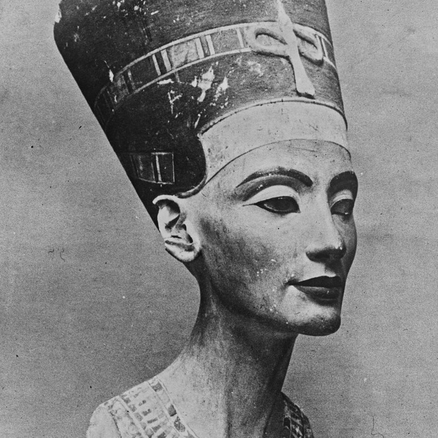 هذه صورة لتمثال نصفي لملكة أو إلهة مصرية قديمة، يُعتقد أنها نفرتيتي. يظهر التمثال النصفي بتفاصيل دقيقة وجميلة للوجه، بما في ذلك ملامح وجه متوازنة وعينين معبرتين. ترتدي الملكة تاجًا مميزًا مزينًا بتفاصيل دقيقة، بالإضافة إلى عقد رائع حول رقبتها. يُظهر التصميم دقة فنية تعكس الثقافة والفن المصري القديم.