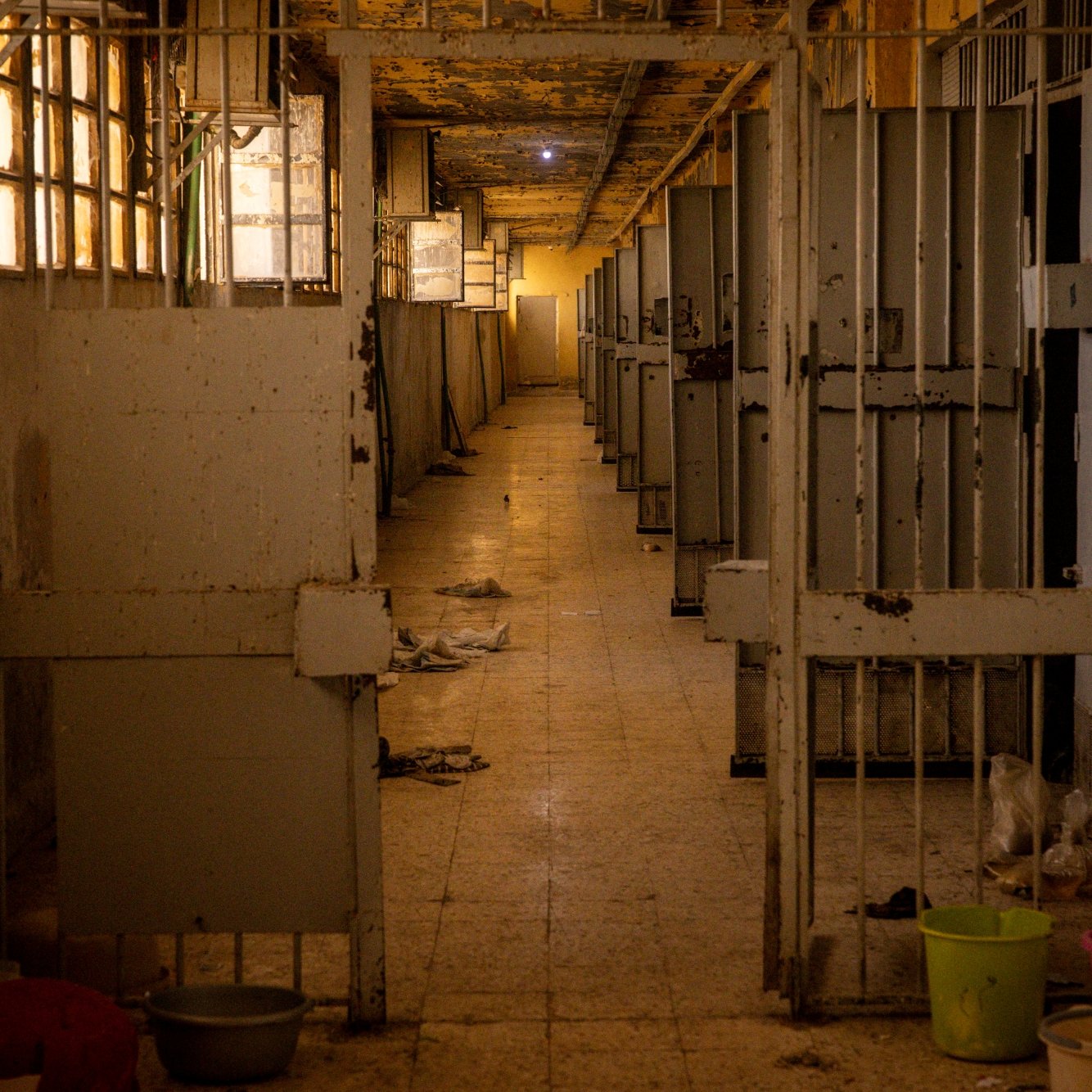 Couloir désert d'une structure, avec des cages vides et des murs en détérioration.