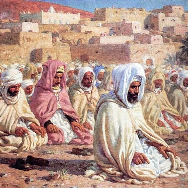 L'image représente un groupe de personnes rassemblées en prière, probablement dans un contexte religieux. Elles sont vêtues de robes traditionnelles et portent des turbans ou des voiles. Les hommes semblent concentrés et méditatifs, assis sur le sol. En arrière-plan, on peut voir une ville avec des maisons aux couleurs claires, sous un ciel bleu, ce qui suggère un environnement désertique ou méditerranéen. L'atmosphère est paisible et spirituelle.