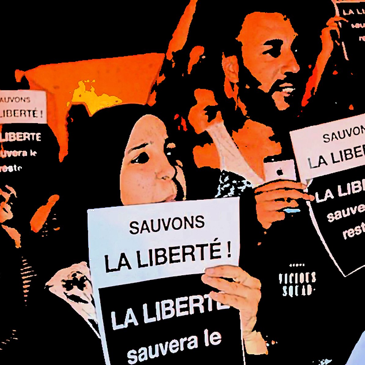 The image depicts a group of people holding up signs with messages in French. The main focus is on two individuals in the foreground. One is wearing a hijab and both are raising their signs high, which read "Sauvons la liberté!" (Save Liberty!). The atmosphere suggests a protest or rally, with a sense of solidarity and determination among the participants. The background is filled with more people and signs, contributing to the overall theme of advocating for freedom.