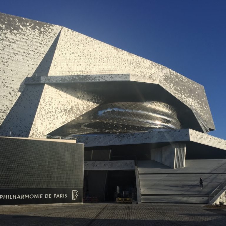 Bâtiment moderne aux formes ondulées, façade métallique, situé à Paris.
