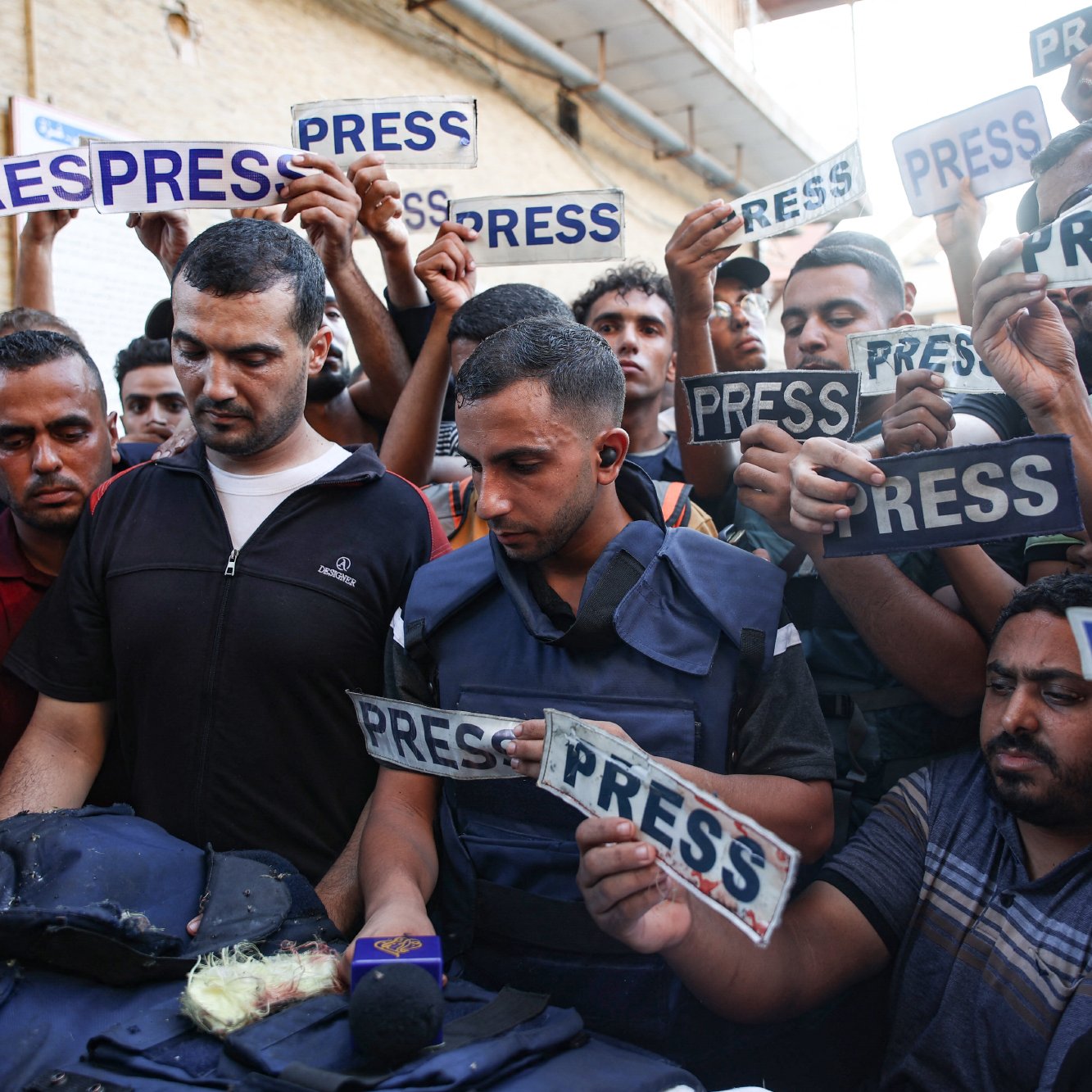 Un groupe de journalistes et de manifestants, brandissant des panneaux "PRESS".