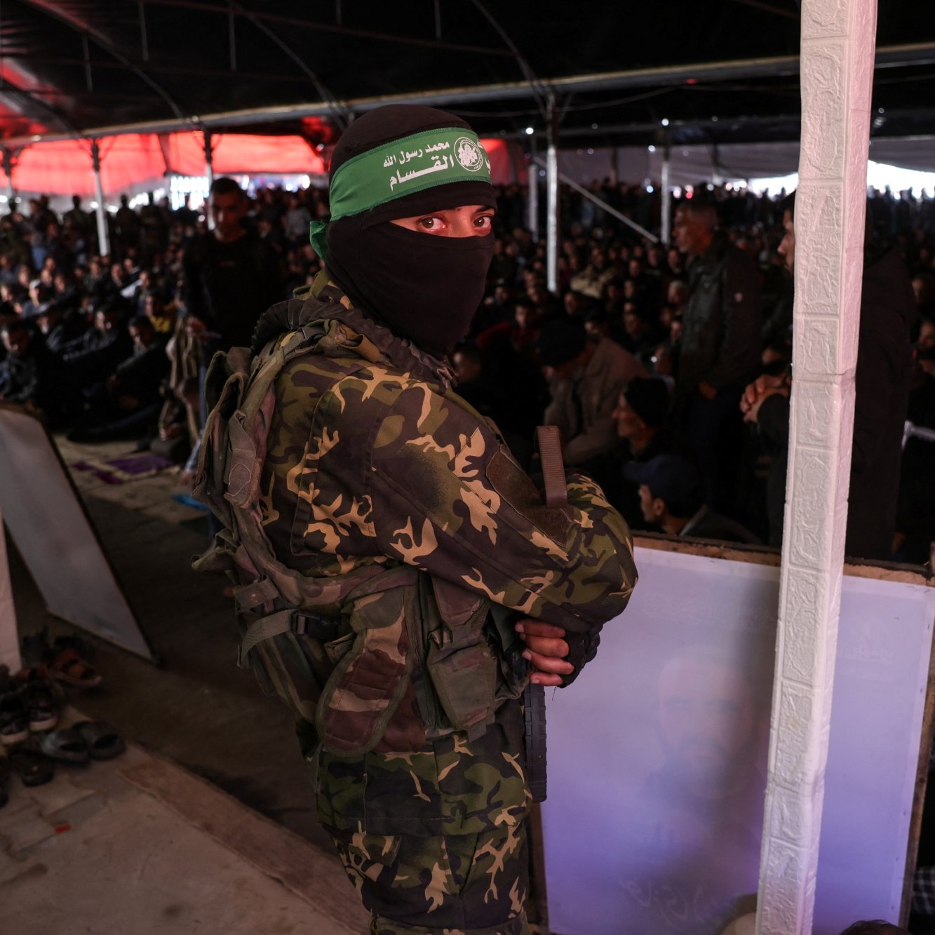 Un soldat masqué en uniforme surveille une grande foule au sein d'un bâtiment.