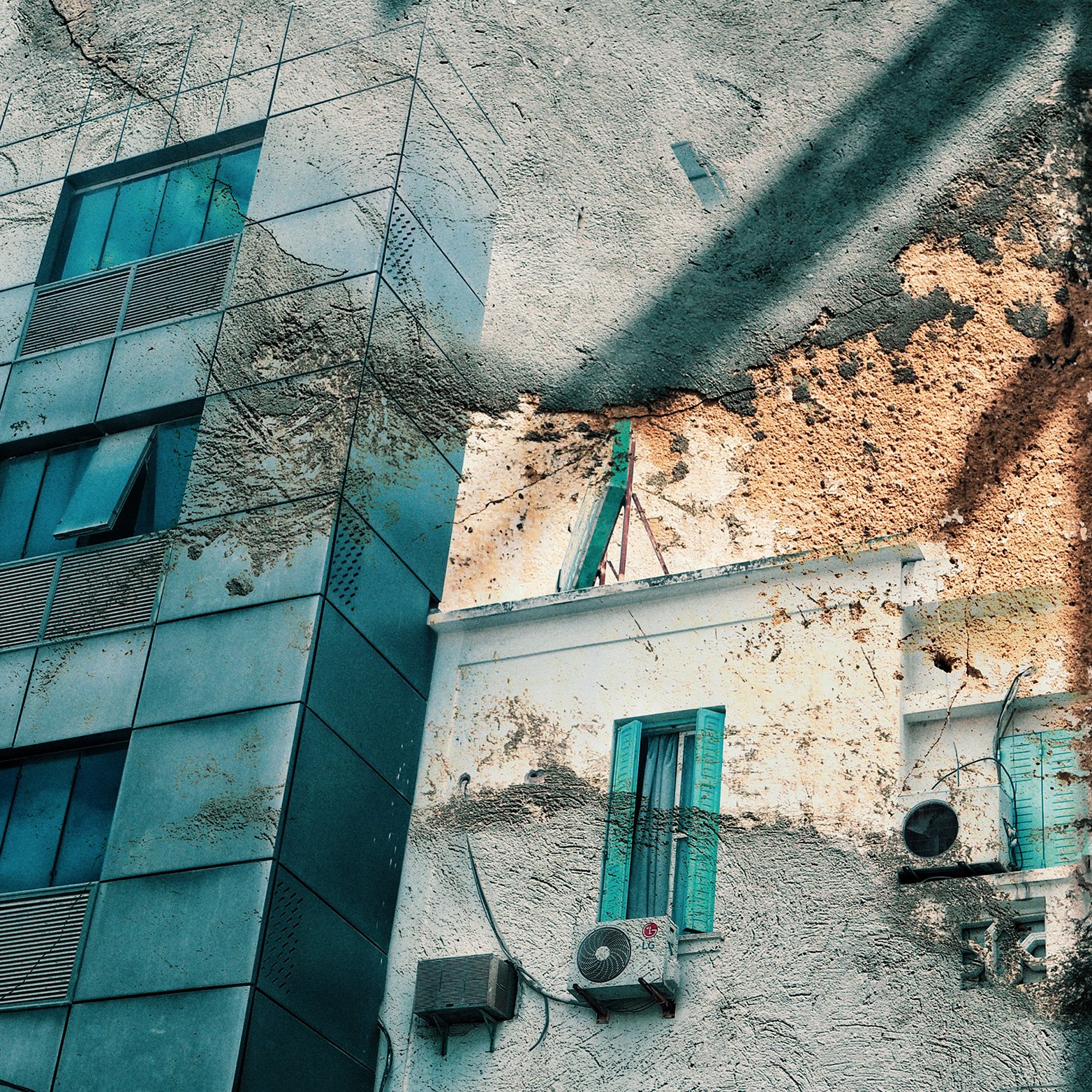 تظهر في الصورة واجهات مباني مختلطة، حيث يُلاحظ وجود مبنى حديث ذو واجهة زجاجية إلى جانب جزء قديم يتسم بالرماد والألوان البنية. الأبواب والنوافذ تحمل طابعًا تقليديًا مع تواجد نوافذ ملونة باللون الأزرق. كما يظهر في الصورة بعض وحدات تكييف الهواء. تتداخل أنماط الضوء والظل، مما يضفي تأثيرًا فنيًا على المنظر.