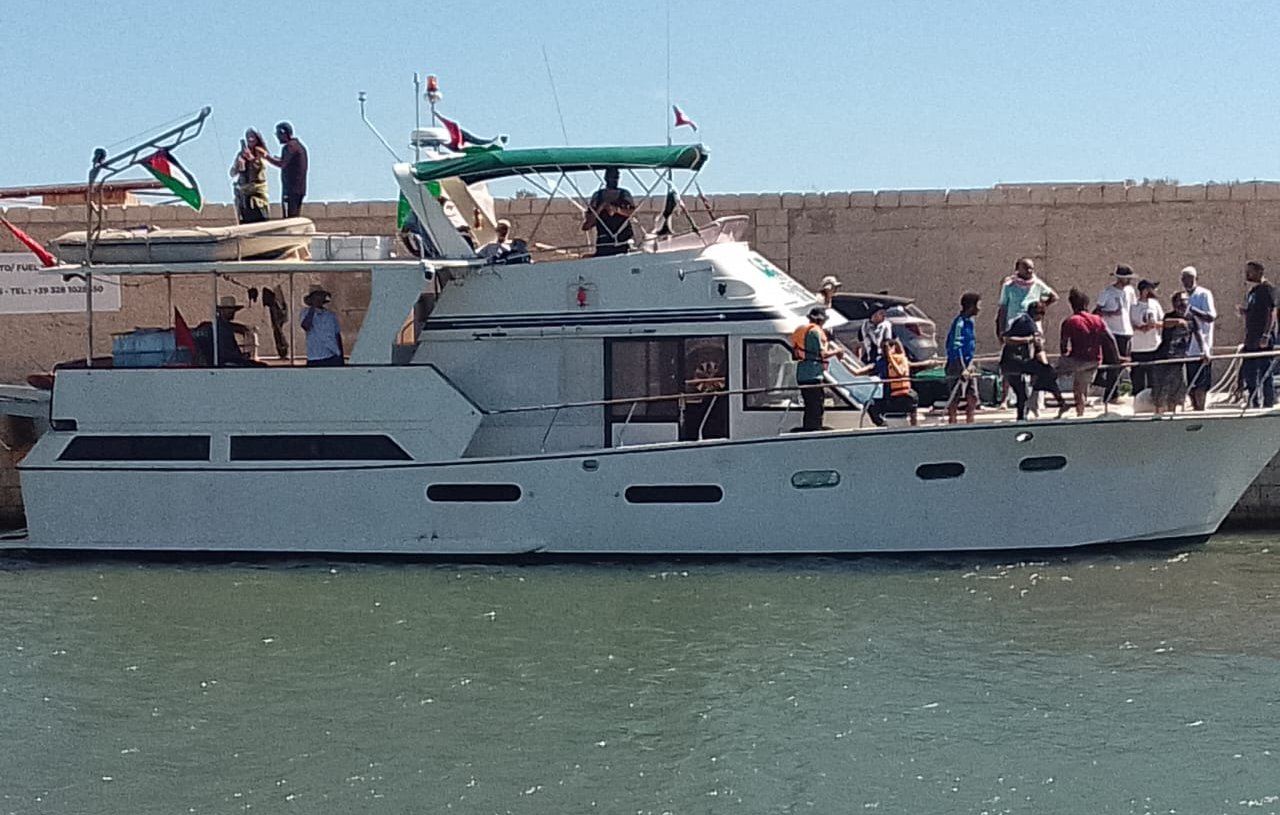 Un bateau à moteur blanc à quai, avec des passagers et un ciel bleu.