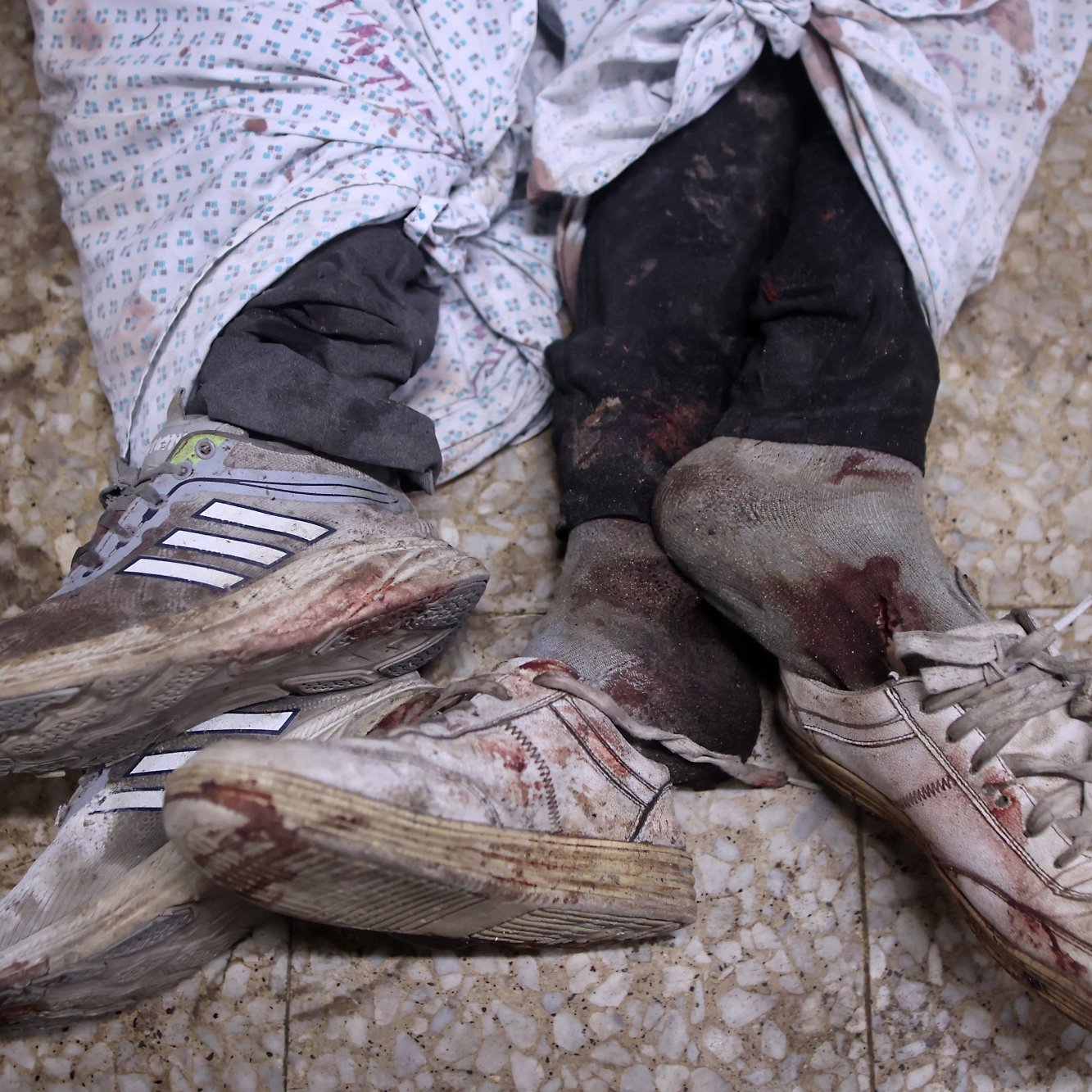Two pairs of blood-stained shoes are visible, partially covered by tattered cloth.