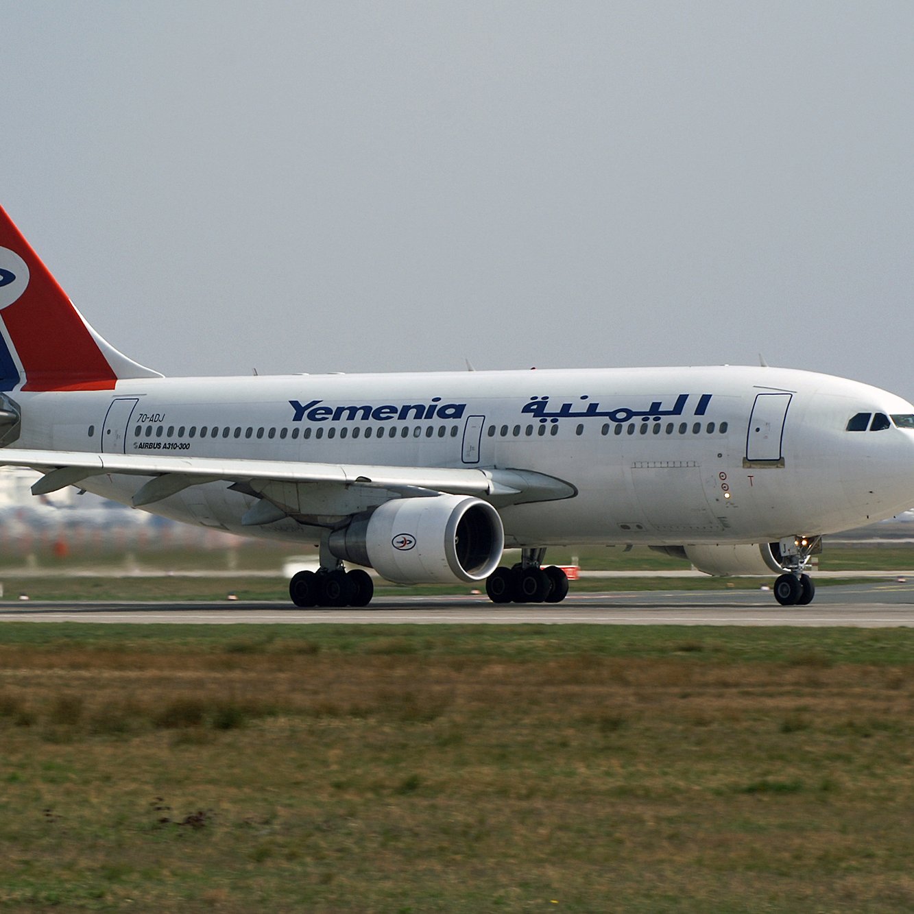Avion de la compagnie Yemenia avec un design aux couleurs rouge, bleu et blanc sur la piste.