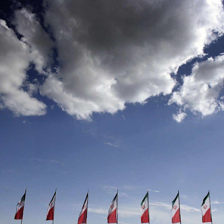 الصورة تُظهر مجموعة من الأعلام، حيث تكون الأعلام مرفوعة بشكل منتظم على طول الجزء السفلي. الأعلام تظهر بألوانها المميزة، مع خلفية من السماء الزرقاء التي تحتوي على بضعة غيوم بيضاء. يبدو أن الأعلام تمثل دولة معينة، والطابع العام للصورة يعطي شعورًا بالاحتفال أو الفخر الوطني.