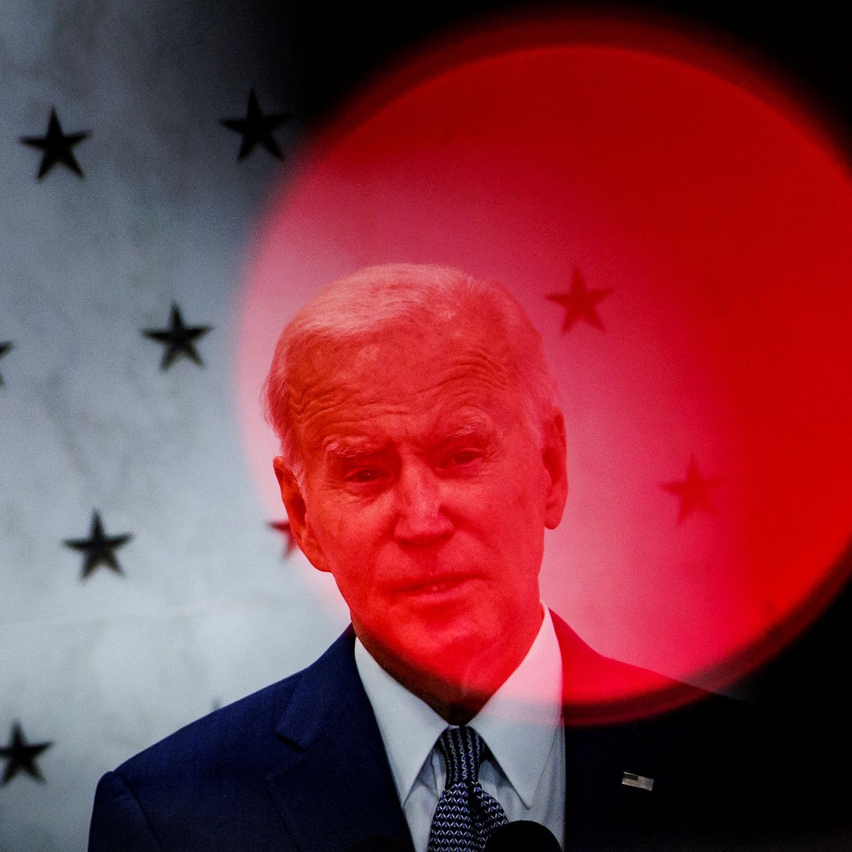 تظهر الصورة شخصاً يقف أمام خلفية بها نجوم، مع تأثير بصري يشير إلى دائرة حمراء غير واضحة. يبدو أن الشخص يتحدث أو يدلي ببيان، حيث يُركَّز الضوء عليه بشكل يجعله بارزاً. الخلفية والظلال تضفي طابعاً درامياً على الصورة.