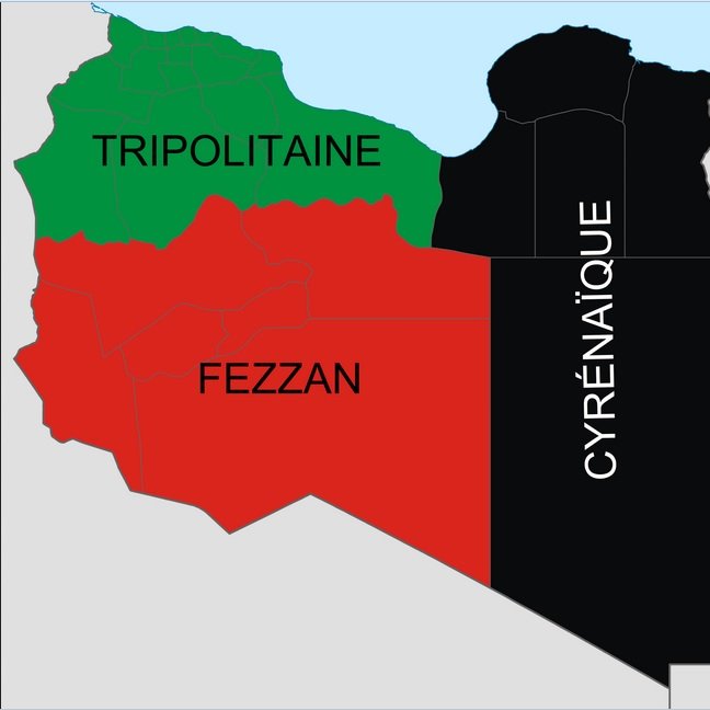 L'image montre une carte de la Libye, divisée en trois régions principales. La partie supérieure est la Cyrénaïque, représentée en noir. La région au centre est le Fezzan, en rouge, tandis que la partie supérieure gauche est la Tripolitaine, indiquée en vert. Chaque couleur représente une région distincte du pays.
