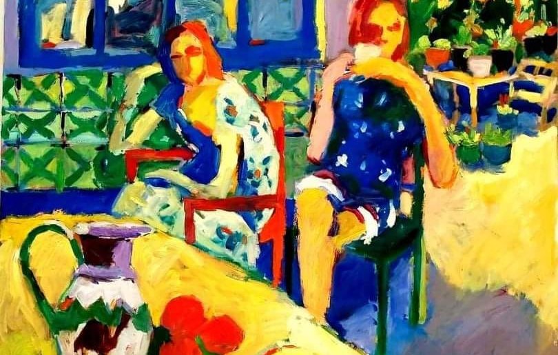 L'image présente une scène vibrante et colorée, avec deux femmes assises sur des chaises. L'une porte une robe bleu foncé, tandis que l'autre est vêtue d'une robe à motifs floraux. Le fond montre une fenêtre avec des carreaux colorés et un jardin verdoyant. Au premier plan, une table est dressée avec un pot et des fruits, ajoutant une touche vivante à la composition. Les couleurs sont éclatantes, donnant une impression de chaleur et de convivialité.
