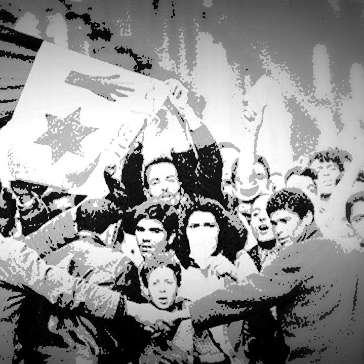 L'image montre une scène de rassemblement populaire où des manifestants brandissent une grande bannière ou un drapeau. Les participants semblent célébrer ou exprimer des revendications, et il y a une forte énergie collective. Certains visages sont visibles, reflétant diverses émotions, allant de la détermination à la joie. La composition en noir et blanc crée une atmosphère nostalgique et dramatique, soulignant l'importance historique de cet événement.