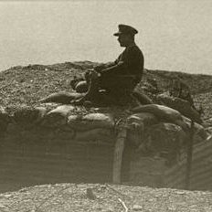 L'image représente un militaire assis sur un tas de terre ou de sacs de sable, surplombant une tranchée. Le soldat est vêtu d'un uniforme, et l'environnement semble être un champ de bataille ou une zone de guerre, probablement datant de la Première Guerre mondiale. Le ton de l'image est sépia, ce qui lui donne un aspect ancien et rétro, amplifiant le sentiment de nostalgie et de gravité de la situation.