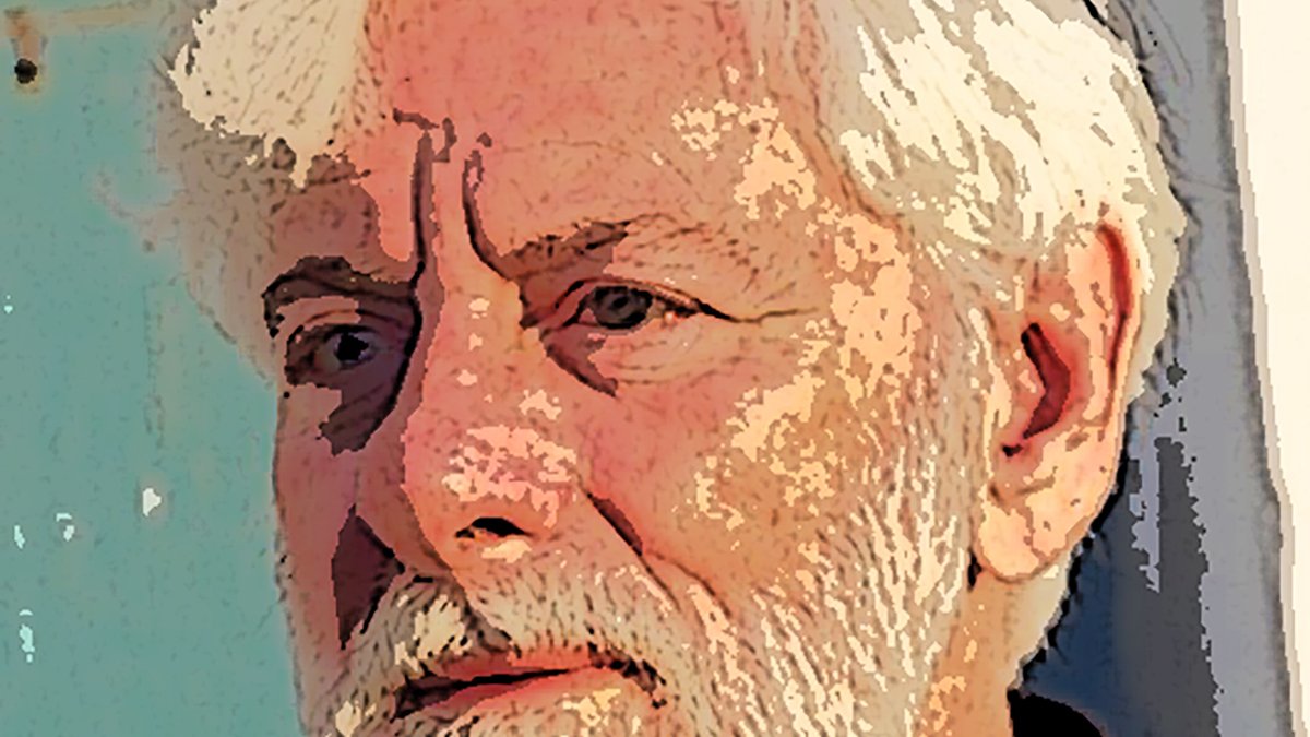 این تصویر یک مرد با موهای سفید و ریش خاکستری را نشان می‌دهد. او به سمت چپ نگاه می‌کند و facial expression او جدی و متمرکز است. پس‌زمینه شامل دیواری با رنگ آبی یا سبز است که ظاهری قدیمی دارد. لباس او تیره و ساده است، و به طور کلی تصویر حس آرامش و تفکر عمیق را منتقل می‌کند.