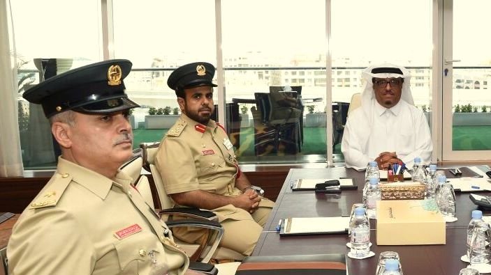 تظهر الصورة مجموعة من الرجال الذين يرتدون زيًا رسميًا في اجتماع. يجلس شخصان على اليسار يرتديان زياً عسكرياً، بينما يجلس الشخص الثالث على اليمين مرتديًا ثوبًا أبيض وعقال. يبدو أنهم يتناقشون حول موضوع مهم، حيث تركز الكاميرا على تعبيراتهم الجادة. في الخلفية، نلاحظ نوافذ كبيرة تُظهر منظرًا خارجيًا، مما يعكس طبيعة المكان وأجواء الاجتماع.