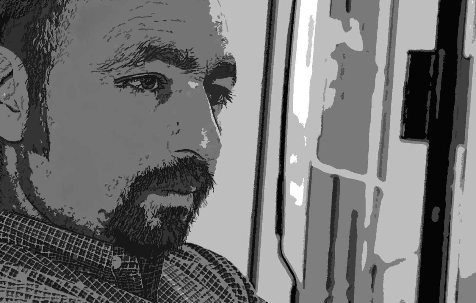 L'image présente un homme dont le visage est partiellement en ombres et lumières, ce qui donne une ambiance introspective. Il semble pensif, regardant dans une direction indéfinie. Les traits de son visage sont marqués, et il a une barbe bien entretenue. Le fond est flou, ce qui permet de concentrer l'attention sur son expression méditative.