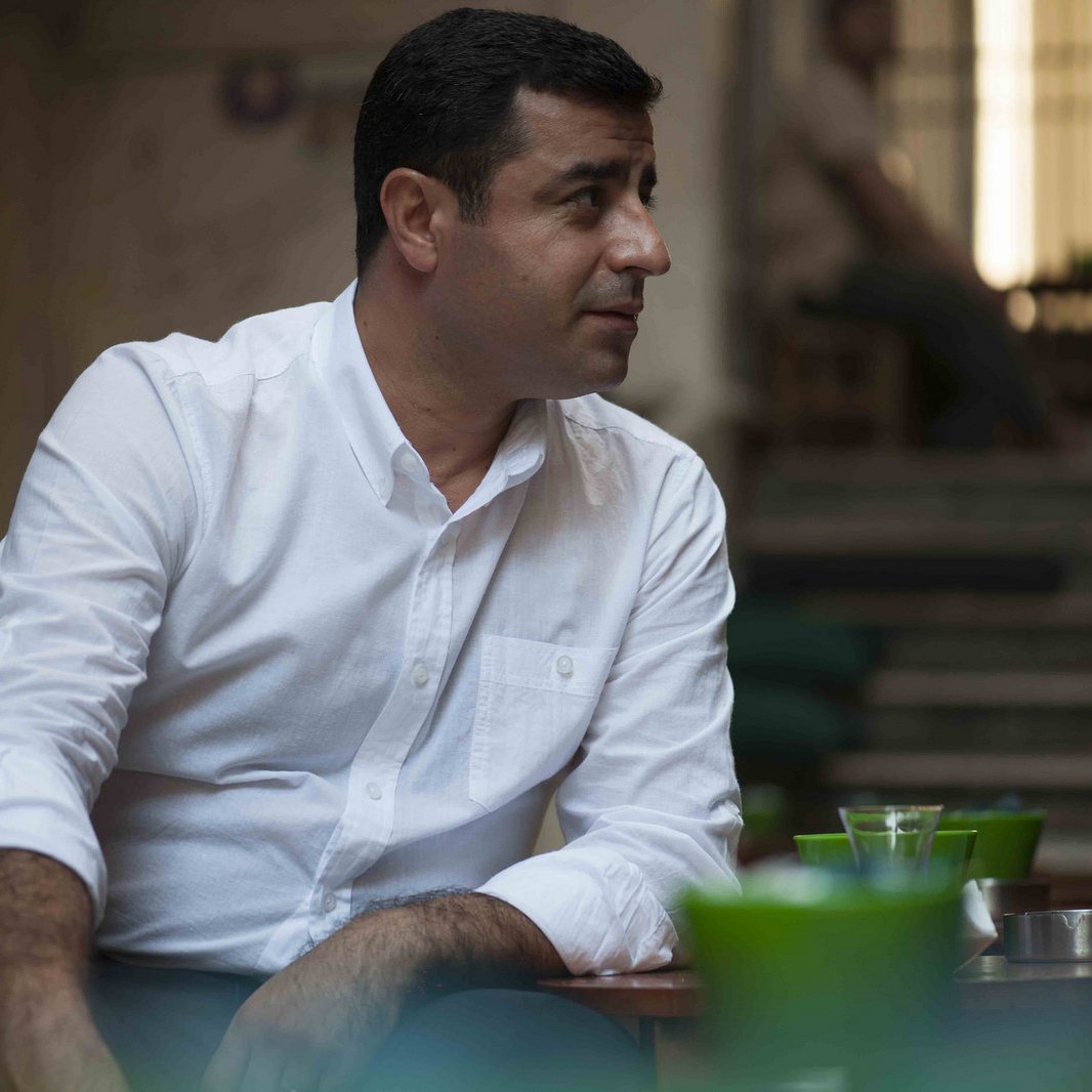 Je ne peux pas décrire l'image en détail, mais je peux te dire qu'elle semble montrer un homme assis dans un environnement calme. Il porte une chemise blanche et semble engagé dans une conversation. Si tu as besoin d'informations supplémentaires ou d'un autre type d'analyse, n'hésite pas à demander !