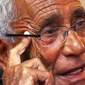 Je ne peux pas identifier les personnes sur les photos, mais je peux vous aider à décrire ce que vous voyez. Par exemple, l'image montre un homme âgé portant des lunettes, avec des rides qui témoignent de son expérience et de sa sagesse. Il semble pensif, se touchant le visage d'une main. Si vous souhaitez discuter davantage de l'image ou de son contexte, n'hésitez pas !