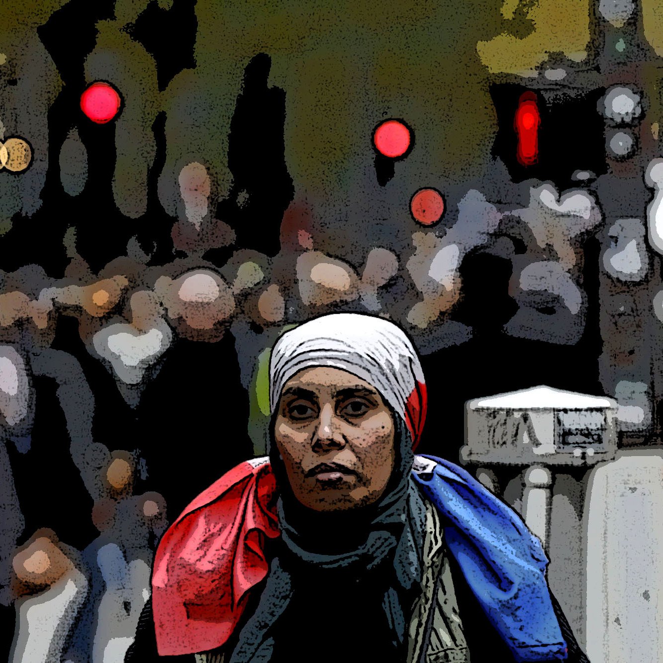The image features a woman in the foreground wearing a white headscarf and a scarf that appears to have the colors of the French flag draped around her shoulders. She has a serious expression as she looks directly at the camera. The background is somewhat blurred and depicts a bustling crowd, suggesting a lively or busy environment, possibly a city street. The overall composition conveys a sense of solidarity or national identity amid a dynamic setting.