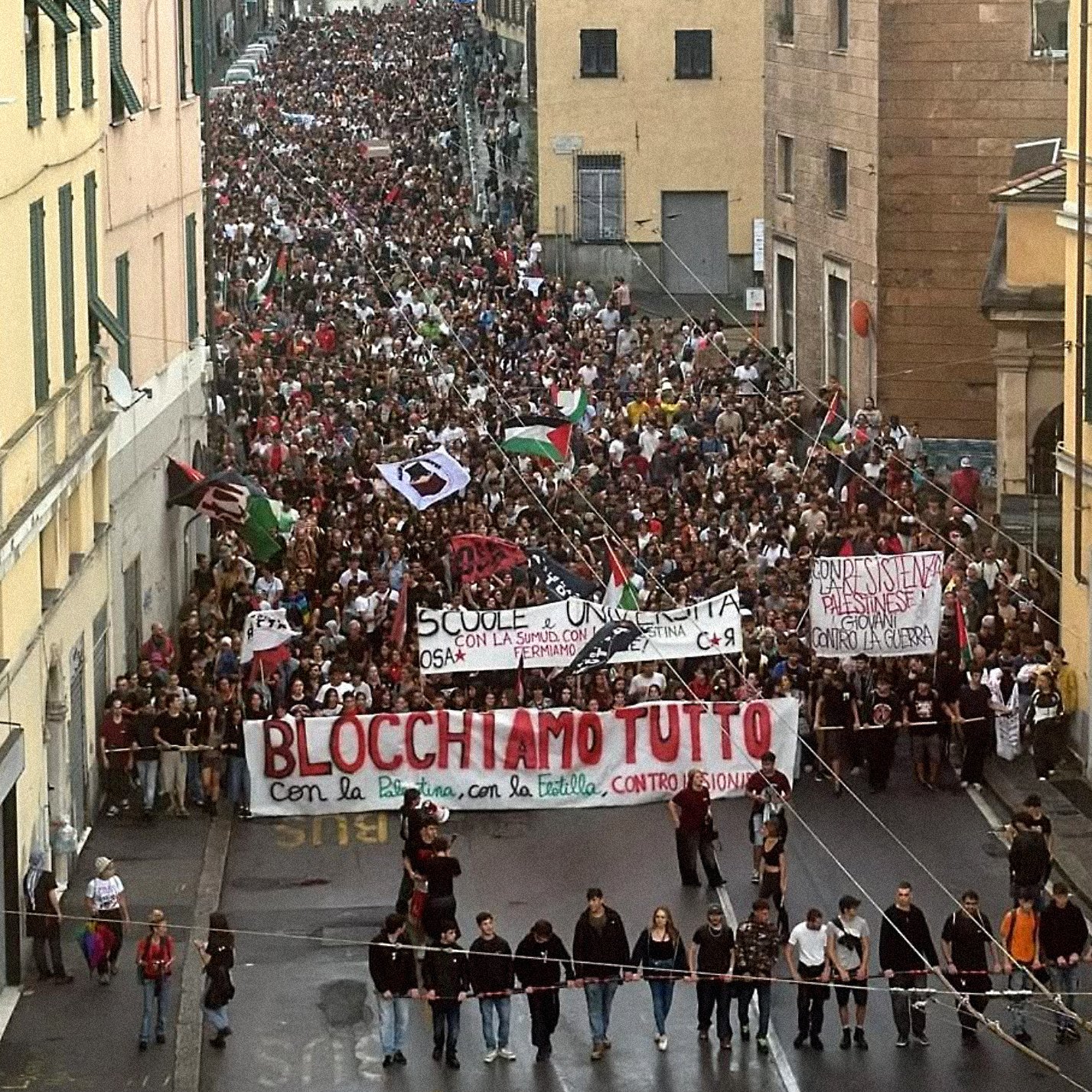Une grande manifestation avec des milliers de personnes et des banderoles dans la rue.