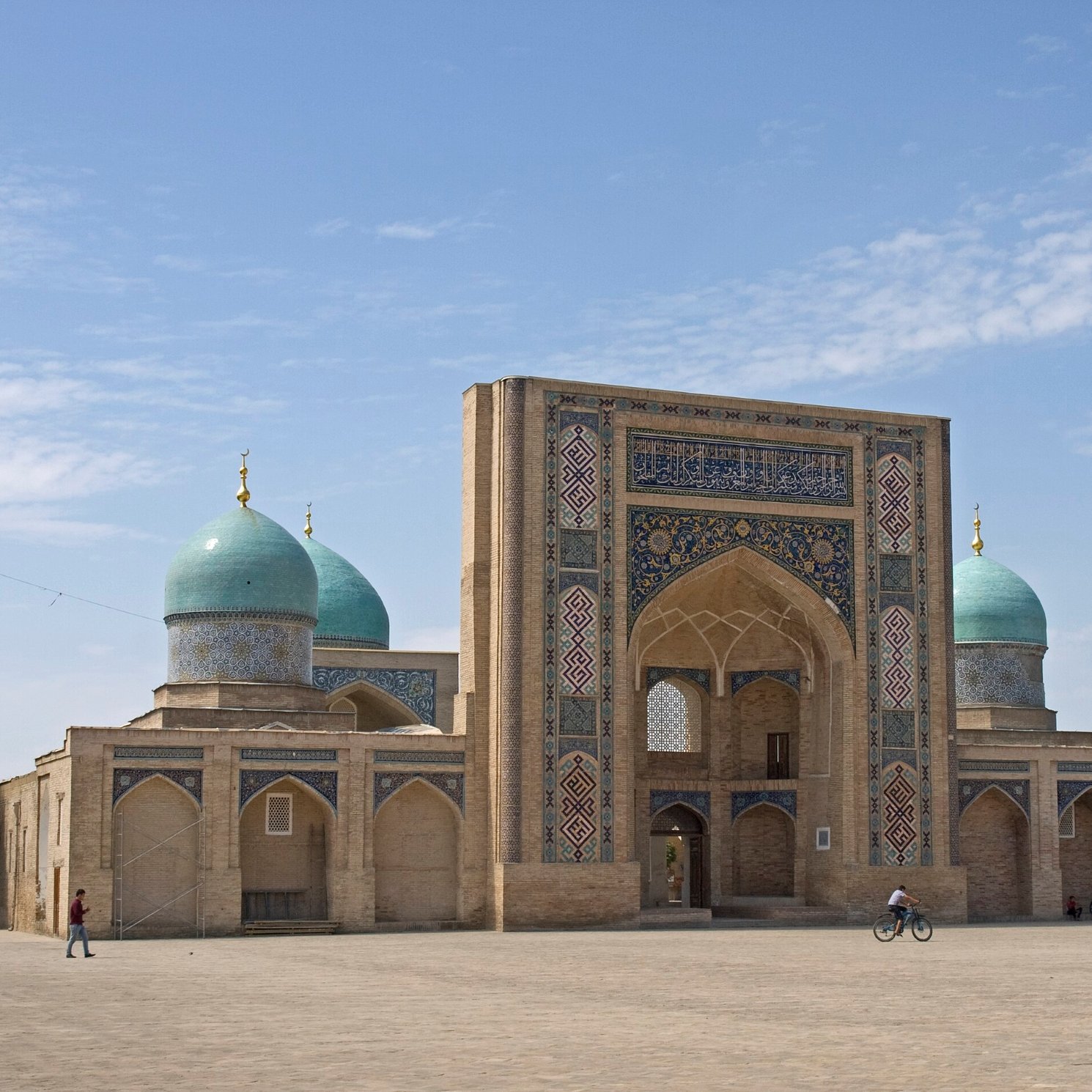 A grand structure with blue domes and intricate patterns, set against a clear sky.