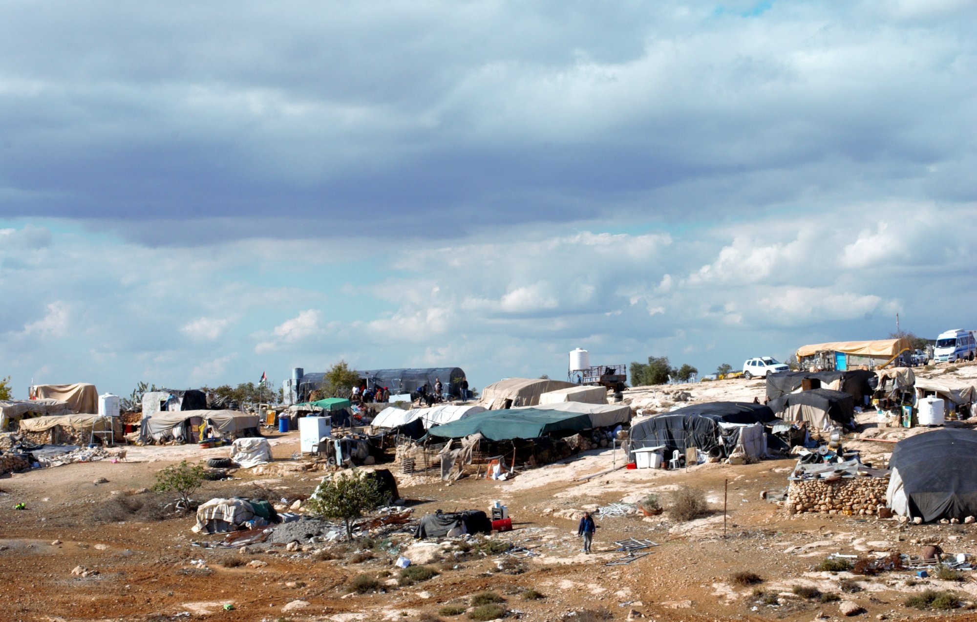 Des tentes éparses sur un terrain rocky, sous un ciel nuageux.