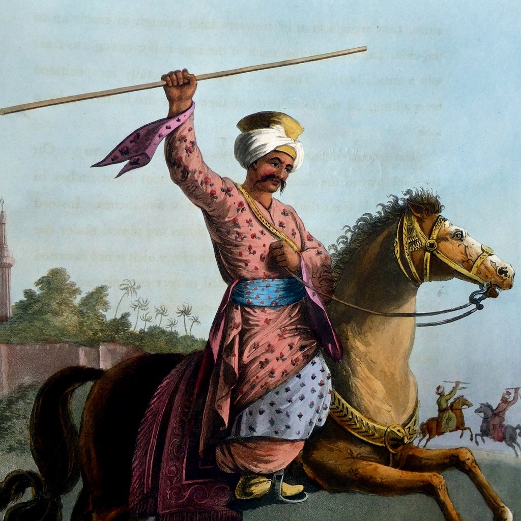 L'image représente un cavalier en tenue traditionnelle. Il porte un turban et des vêtements colorés ornés de motifs, avec une ceinture large. Le cavalier est en train de tenir un long bâton levé, semblant exprimer force et détermination. Il est monté sur un cheval puissant, qui avance au galop. En arrière-plan, on peut apercevoir d'autres cavaliers, ce qui suggère une scène dynamique. L'environnement semble indiquer un paysage désertique ou aride, renforçant le caractère historique de l'image.