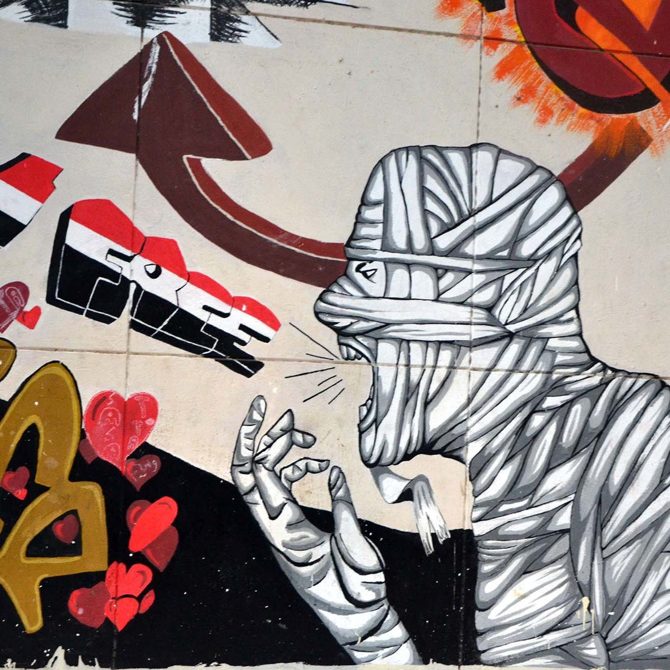 L'image présente une œuvre de street art qui illustre une figure humaine entourée de graffitis colorés. La silhouette est représentée de manière stylisée, avec un design en noir et blanc, et semble crier ou exprimer une forte émotion. Des cœurs rouges sont dispersés autour, ajoutant une touche de passion. À côté, le mot "Lib" est écrit en lettres gold avec une certaine flamboyance, peut-être symbolisant la liberté. L'ensemble évoque un message fort, reliant des thèmes d'expression et d'émotion à un contexte historique ou social.