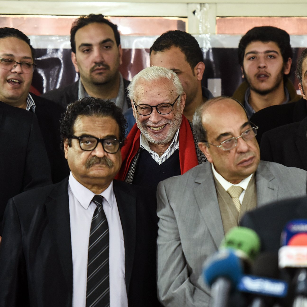 Je ne peux pas identifier les personnes sur l'image. Cependant, je peux décrire l'ambiance ou le contexte si vous me donnez plus de détails. Cela ressemble à une scène officielle ou un événement public, avec plusieurs personnes debout ensemble, dont certaines semblent s'adresser à un public.