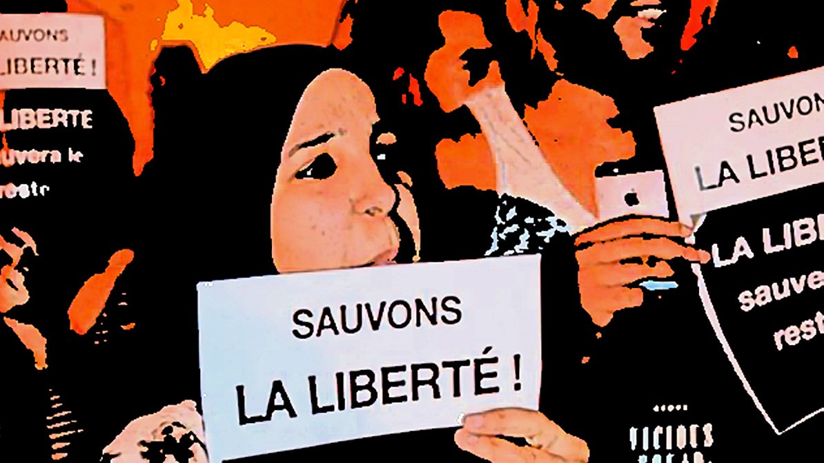 L'image montre un groupe de personnes tenant des pancartes sur lesquelles on peut lire "Sauvons la liberté !" et "La liberté sauvera le reste...". Il semble s'agir d'une manifestation ou d'un rassemblement pour défendre la liberté, avec des participants affichant des expressions engagées et déterminées. L'ambiance semble être à la mobilisation et à la solidarité.