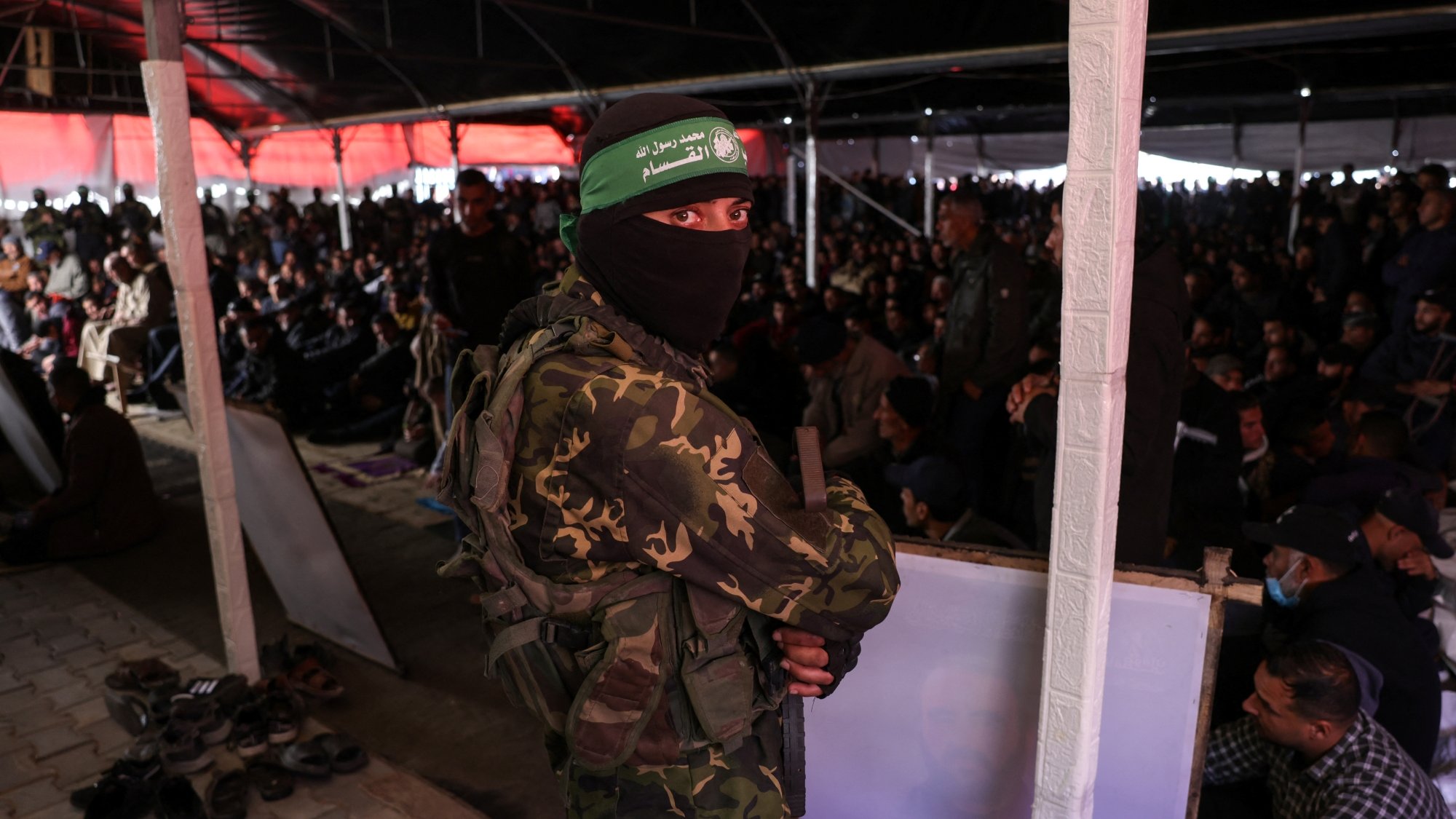 Un soldat masqué en uniforme surveille une grande foule au sein d'un bâtiment.