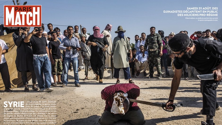 L'image semble représenter une scène dramatique dans un contexte de conflit. Elle montre un groupe de personnes, probablement dans un environnement de guerre, où des individus armés sont présents. Au premier plan, une personne est à genoux, apparemment soumise à des actes de violence, entourée par d'autres qui semblent observer la situation. L'atmosphère est tendue et illustre des thèmes de violence et de conflit, mettant en évidence des tensions entre différentes factions. Les éléments de l'image témoignent d'un contexte difficile et tragique.