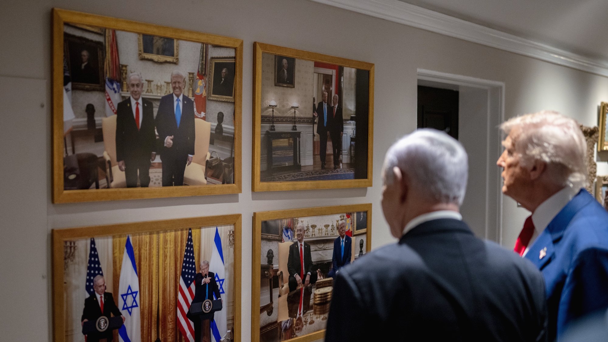 دو مرد در کت و شلوار در کنار یکدیگر ایستاده‌اند. تصاویر آن‌ها بر دیواری قاب شده‌اند.