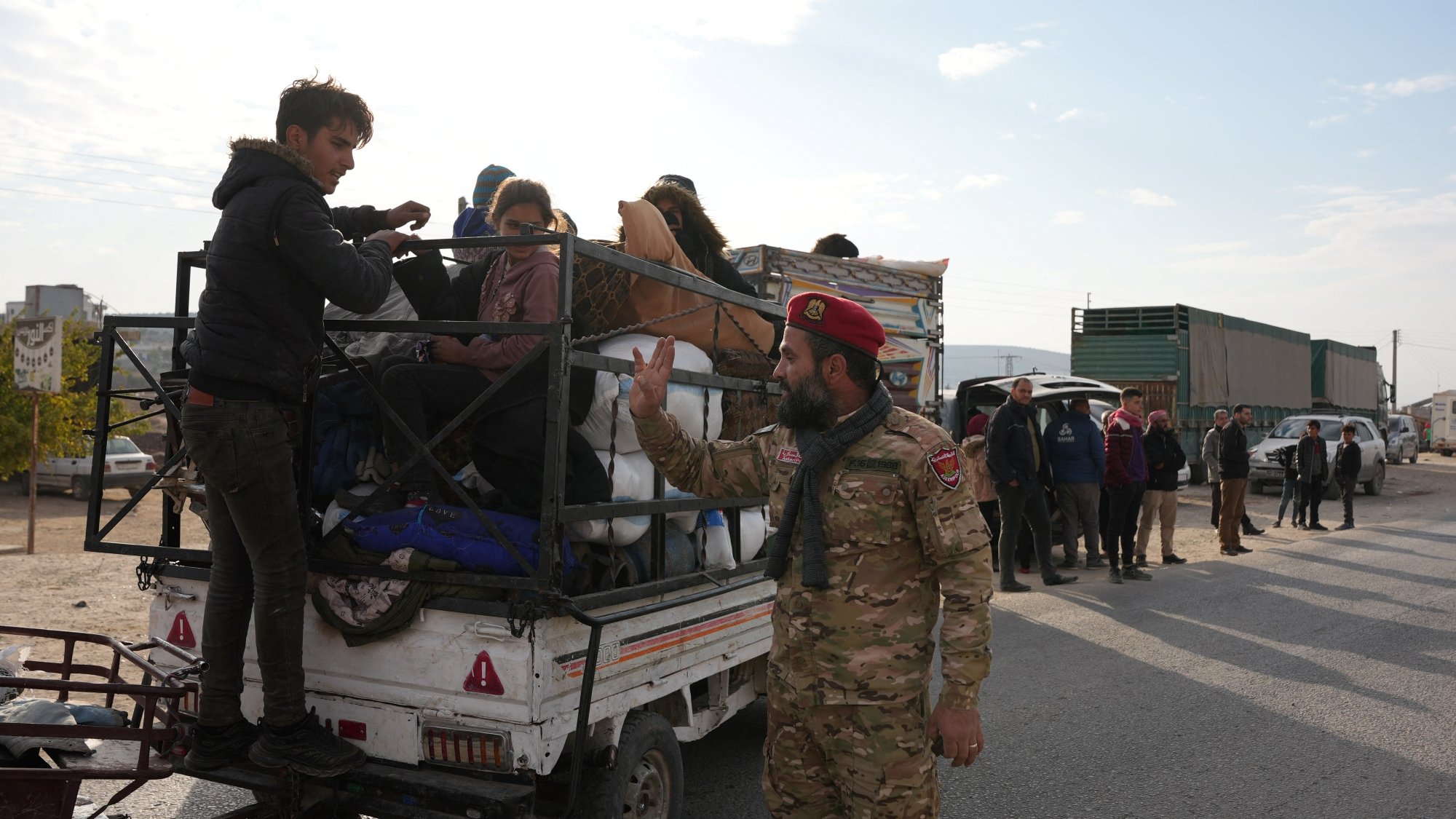 تصویری از یک خودرو باربری با مسافران و یک سرباز که در حال صحبت با آنهاست.