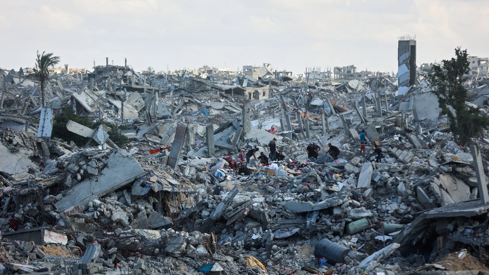 Destruction massive avec décombres et silhouettes humaines cherchant des survivants.