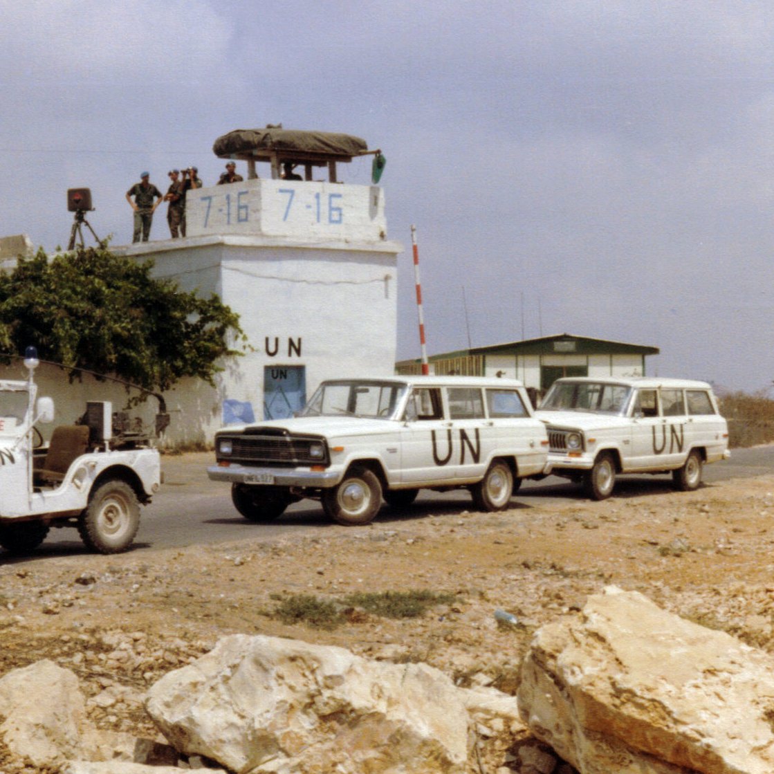 Convoi de véhicules de l'ONU près d'une tour de surveillance militaire.