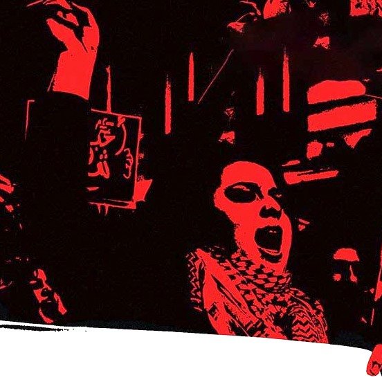 L'image présente une scène expressive et énergique, probablement de manifestation ou de rassemblement. On y voit une personne au premier plan qui lève son bras, suggérant un appel à l'action ou une déclaration de protestation. L'arrière-plan est dominé par des couleurs sombres, ce qui intensifie le sentiment de détermination. Des affiches ou des slogans en arabe sont visibles, renforçant l'idée d'un message collectif. L'atmosphère évoque un fort engagement et une passion pour une cause.