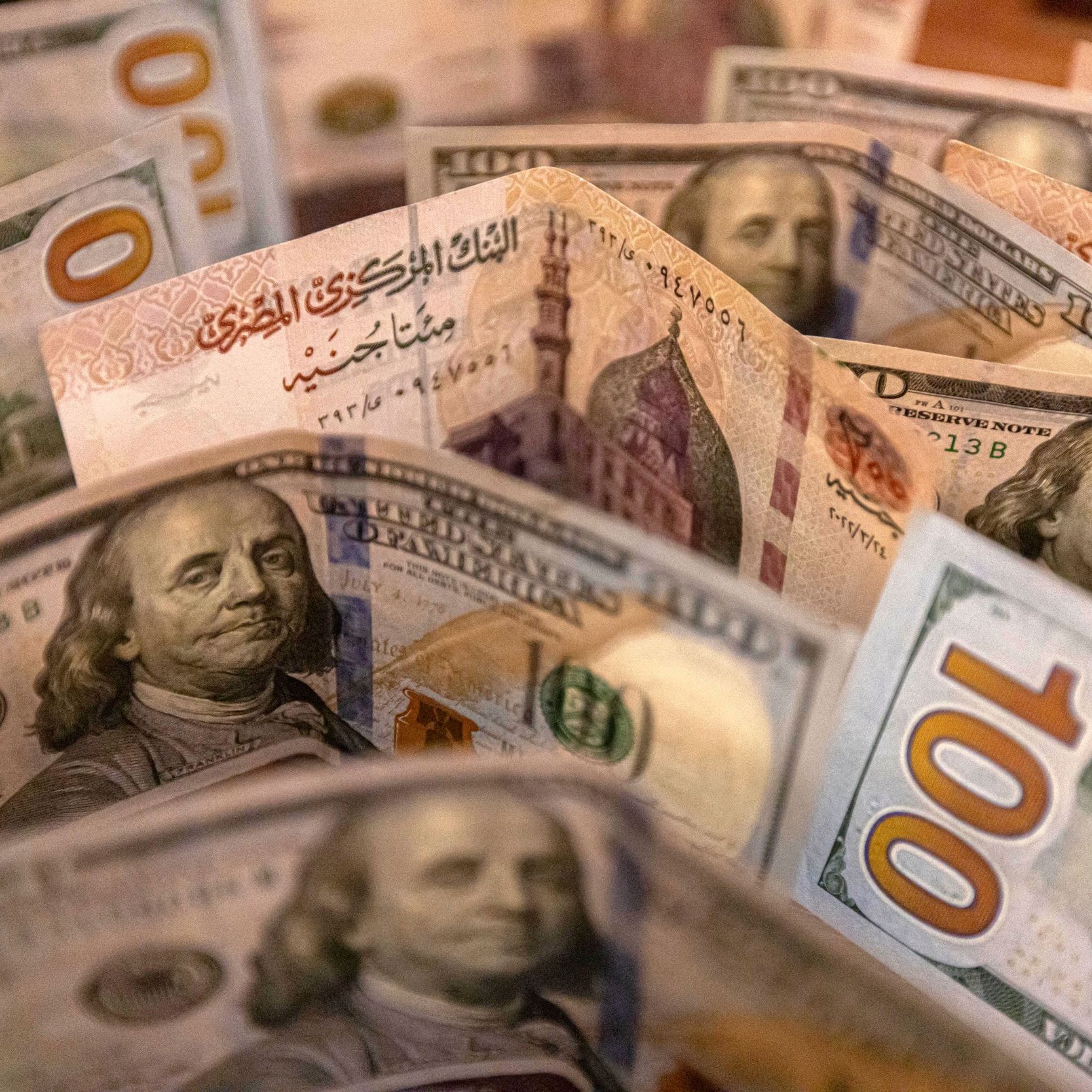 L'image montre un assortiment de billets de banque, probablement des dollars américains. On peut voir plusieurs billets de 100 dollars, avec des illustrations de Benjamin Franklin, ainsi que d'autres détails de la conception des billets. Les billets sont disposés de manière à créer une sorte de fan, mettant en évidence les différentes couleurs et motifs.