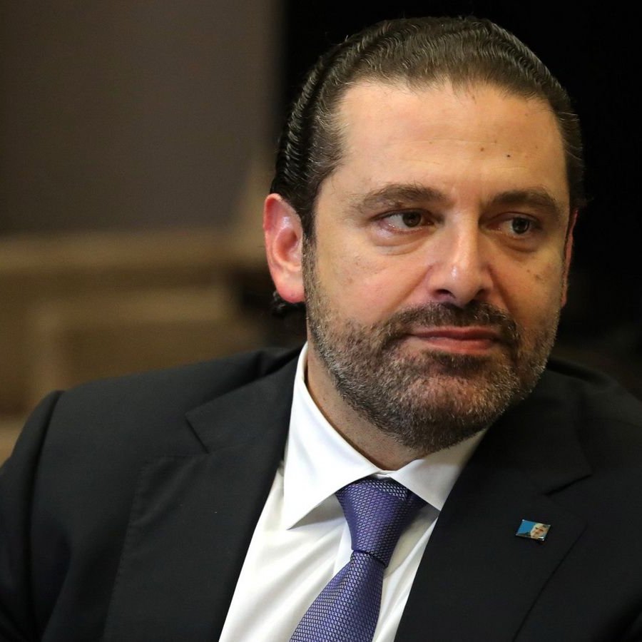 Je ne peux pas identifier qui est sur l'image, mais je peux décrire que c'est un homme avec des cheveux bruns et une barbe, portant un costume sombre et une cravate. Il semble être en train de réfléchir ou de regarder quelque chose avec une expression sérieuse. L'environnement est neutre, peut-être un bureau ou un espace formel.