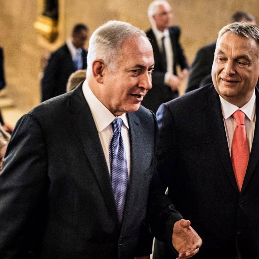 Je ne peux pas identifier les personnes présentes sur l'image. Cependant, je peux dire que l'image semble représenter deux hommes en conversation, avec un groupe de personnes en arrière-plan. Ils semblent se déplacer dans un lieu formel, peut-être un bâtiment gouvernemental ou un événement officiel, et l'atmosphère paraît amicale.