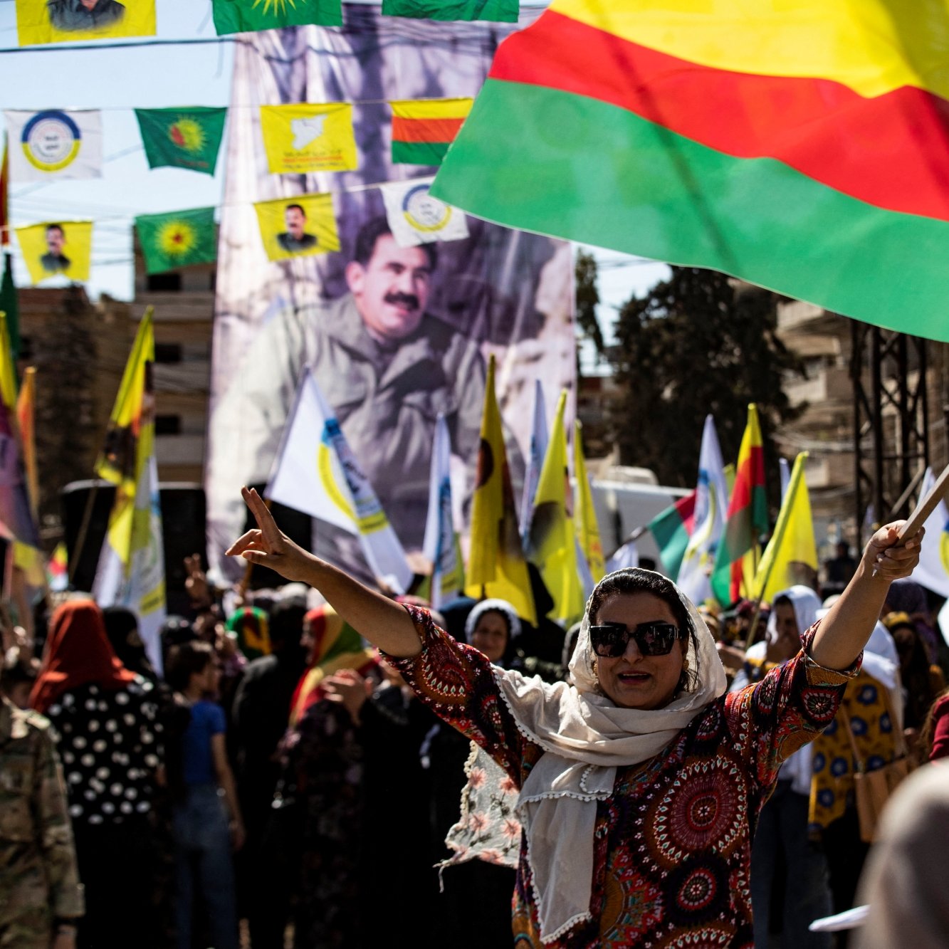 مردم در حال جشن و تظاهرات هستند، پرچم‌های رنگی در دست دارند و شور و شوق به وضوح حس می‌شود.