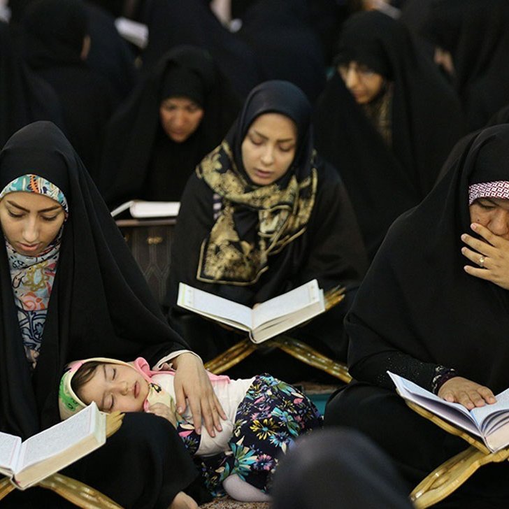 در تصویر گروهی از زنان با چادرهای سیاه در حال مطالعه قرآن دیده می‌شوند. بعضی از آن‌ها در حال خواندن هستند و توجه عمیقی به کتاب دارند. همچنین، یک کودک در آغوش یکی از زنان خوابیده است. به‌طور کلی، فضایی معنوی و پر از تمرکز در این تصویر وجود دارد.