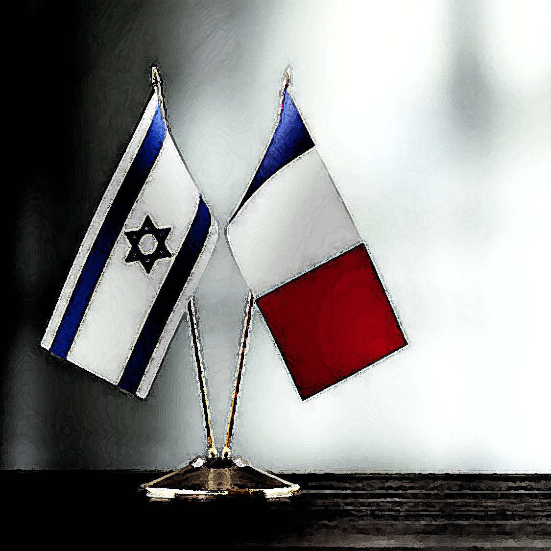 The image features two small flags positioned on a surface. One flag is the national flag of Israel, characterized by its blue and white colors and a Star of David in the center. The other flag is the national flag of France, which consists of three vertical stripes: blue, white, and red. The flags are mounted on small stands, standing together side by side, against a softly blurred background.