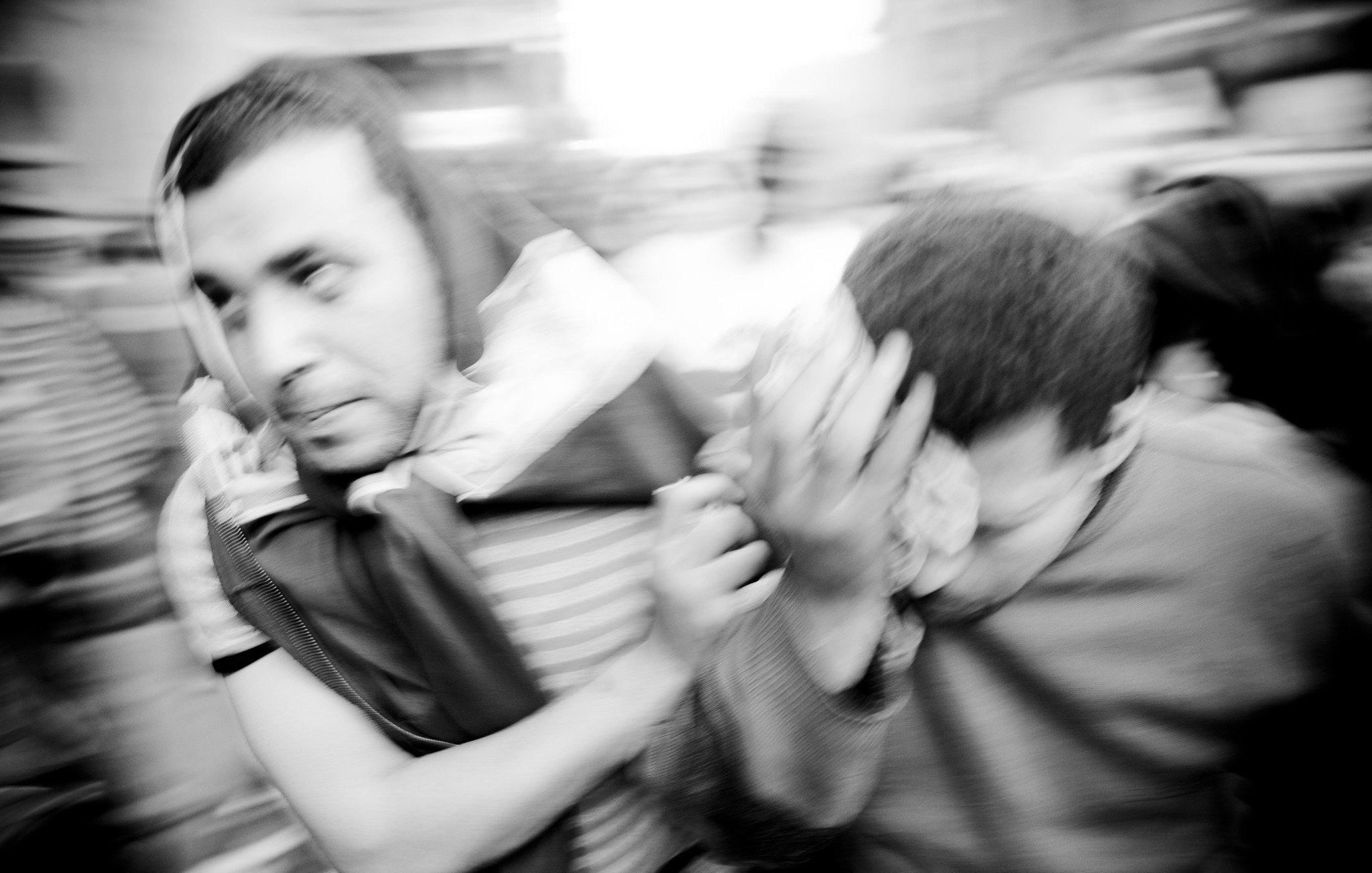 تظهر الصورة رجالاً يتجهون بسرعة في مشهد مزدحم، حيث يبدو أنهم في حالة من الحركة العفوية. الملابس التي يرتدونها متنوعة، ومن الواضح أن هناك نوعاً من التوتر أو الاضطراب في الوضع. الخلفية غير واضحة بسبب الضبابية، مما يعكس شعوراً بالسرعة أو الارتباك. الأربعاء وشعاراتهم تظهر تشويشاً في المشهد، مما يضيف إلى الديناميكية العامة للصورة.