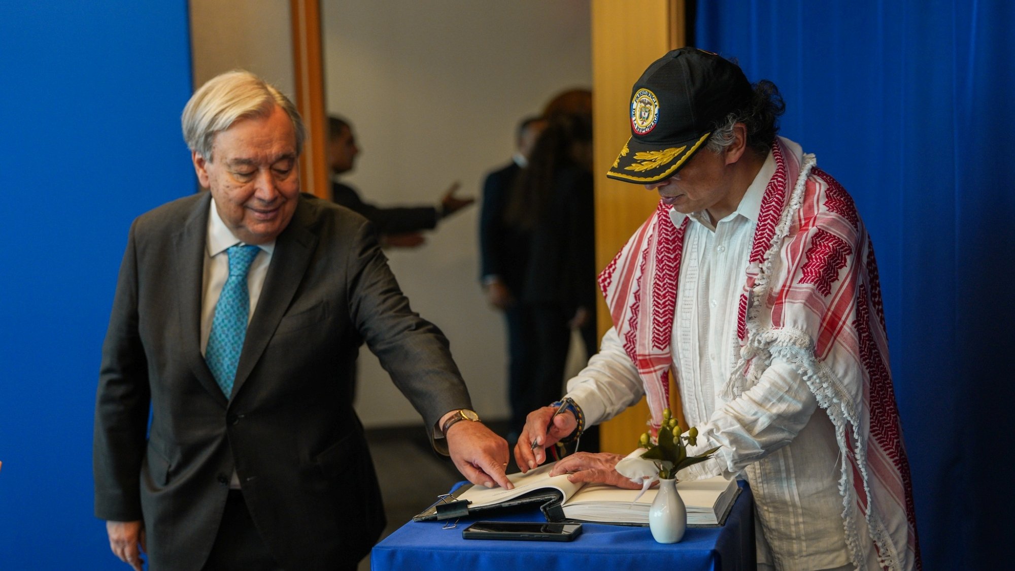 دو مرد در یک اتاق هستند. یکی در حال نوشتن در کتابی روی میزی کوچک است و دیگری نظاره می‌کند.