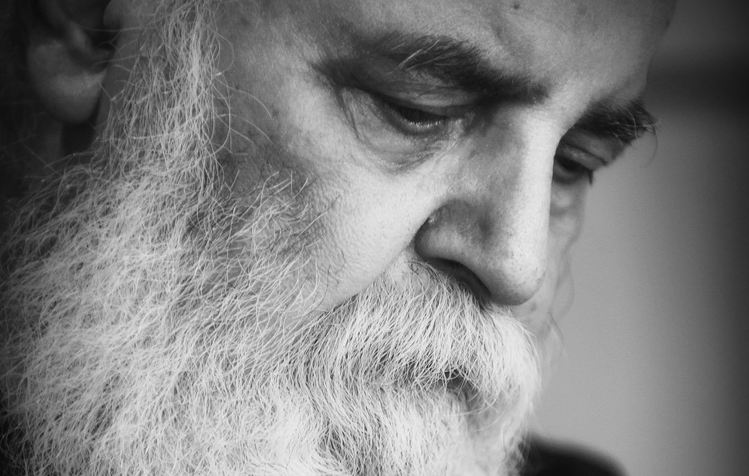 L'image montre un homme âgé avec une longue barbe blanche. Son expression est pensive et introspective, les yeux baissés. L'éclairage est doux, créant un contraste qui met en valeur les détails de son visage et de sa barbe. L'ensemble donne une ambiance de réflexion et de sérénité. La photo est en noir et blanc, ce qui accentue la gravité et la profondeur des émotions.