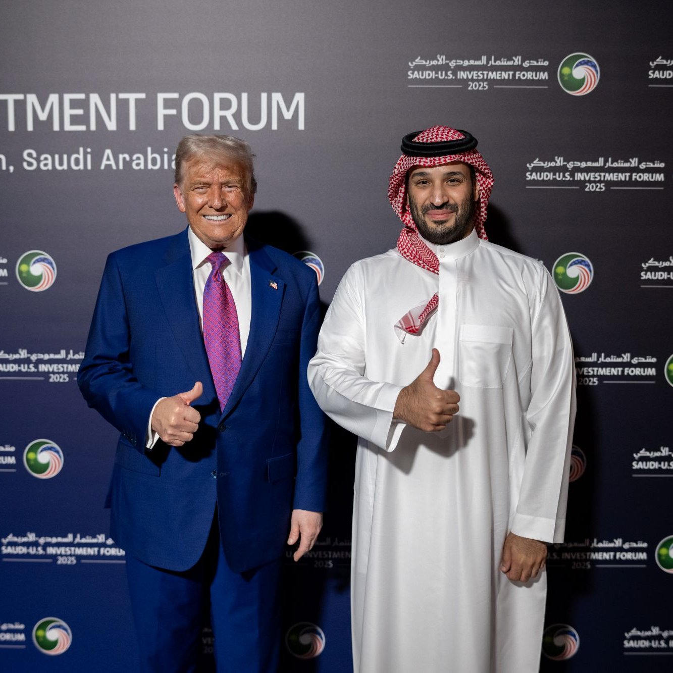 Deux hommes souriants, l'un en costume, l'autre en tenue traditionnelle, posent ensemble.