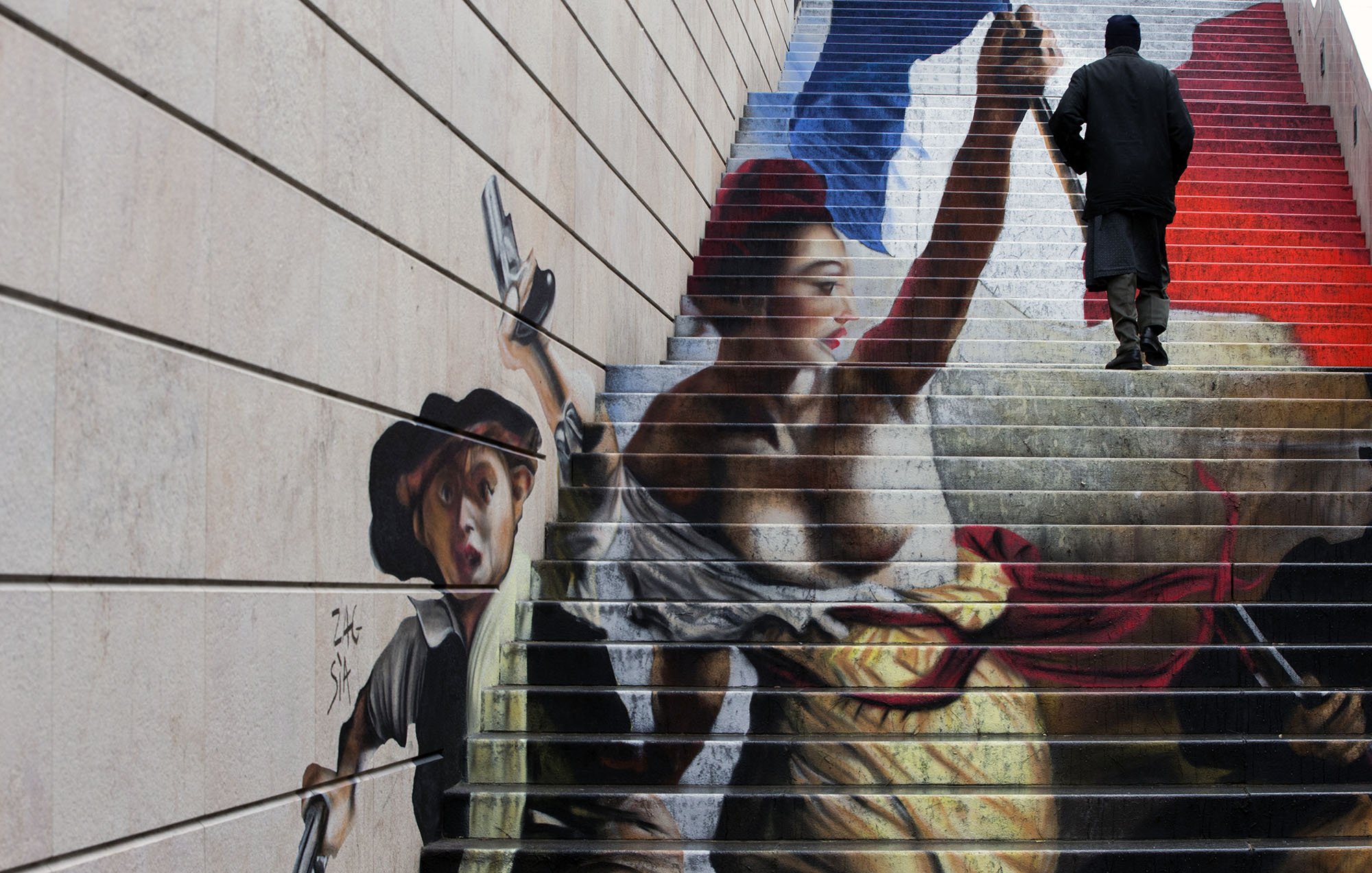 L'image montre une fresque peinte sur des marches d'escalier. On y voit une scène dynamique, représentant une femme aux vêtements colorés, brandissant une arme et symbolisant la liberté. À ses côtés, un jeune garçon semble se joindre à elle, tenant un pistolet. En arrière-plan, on remarque des teintes qui évoquent le drapeau français, avec des nuances de bleu, blanc et rouge. Une personne en noir monte les marches, ajoutant une dimension de mouvement à l'œuvre. Cette fresque combine art et engagement, reflétant des thèmes de révolution et de lutte.